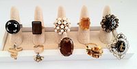Photo showing all 10 vintage cocktail rings displayed on a ring holder stand, all arranged in two rows with various designs including stones, pearls, and ornate silver work.