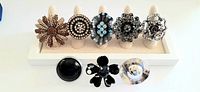 Front view of 8 large vintage rhinestone cocktail rings displayed on ring holders showing detailed rhinestone and metalwork designs.