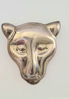 Front view of the silver panther head brooch with detailing of the facial features and tarnish visible.