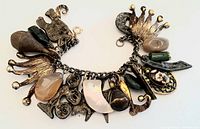Close-up image of the vintage charm bracelet showing varied chunky metal charms and natural stones including a crown charm and animal figure.