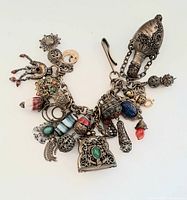 Full view of the vintage India-themed beaded charm bracelet showing all attached charms including a large bell-shaped charm and multicolored beads.