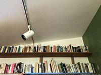 Wide view of wooden shelves filled with assorted hardcover and softcover books in various colors and sizes, arranged mainly vertically with some horizontally.