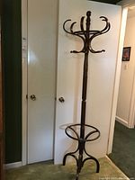 Full view of the wooden coat rack showing height and overall shape including base and hooks.
