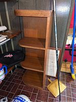 Wooden corner media shelf showing three shelves with rounded edges and stained finish, positioned in corner against paneled wall.