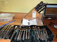 Full view of the RWP pewter flatware set including forks and spoons laid out on dark green fabric, Cutco knife block with knives behind.