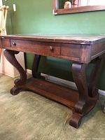 Front and side angle view of the vintage wooden desk showing drawer, carved legs, and surface conditions.