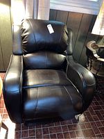 Front view of the brown faux leather electric recliner chair showing padded armrests and cushioned backrest.