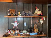 Shelves displaying assorted figurines, glass art, metal, and wood decorative items including a sailboat, stars, and clown figures