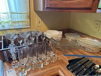 Overview of glassware, including margarita glasses, tall glasses, and casserole dishes on a wooden countertop.