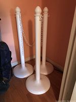 Photo showing three white plastic stanchions arranged with connected white plastic chain