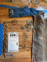 Overview of sterling silver charm bracelet with charms, multiple chains, and fabric pouches on wooden surface.