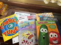 Photo of assorted sheet music and music books featuring cartoon and TV show themes like SpongeBob SquarePants, Veggie Tales, Sesame Street, Star Trek, and Cartoon Tunes book.