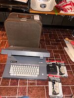Smith Corona SL 500 electric typewriter with keyboard and three unopened correcting cassette packs on tile floor.