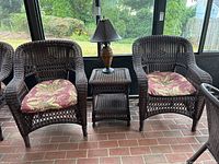 Two wicker chairs with seat pads flanking matching wicker side table