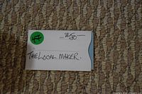 Photo of $50 gift certificate from The Local Maker with handwritten details and green sticker on beige carpet background.