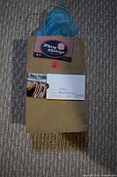 Image of a brown paper gift bag with blue tissue paper, a card and gift certificate for Mary Kathryn Ladies Shop attached.