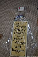 Photo of a rectangular wooden plaque with motivational text wrapped in clear plastic with a ribbon at the top.