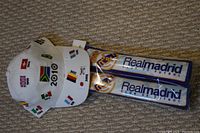White Euro 2010 soccer hat with multiple flags and two blue Real Madrid clappers on carpeted floor.
