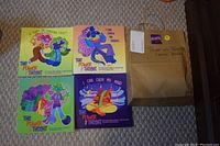 Photo of 4 colorful children's books from 'The Power of Thought' series laid out on carpet beside a brown shipping box labeled with 'Power of Thought Series Books'. The book covers show cartoon characters and titles related to emotions and thoughtfulness.
