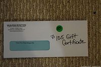 Photo of an envelope containing a $105 gift certificate from Warkentin's Plumbing with company logo and address, and handwritten note indicating value.
