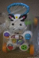 Photo of a Fisher Price zebra-themed kids walker wrapped in plastic, showing the front with colorful buttons and blue handlebar.
