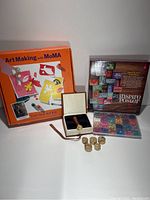 Wide photo showing the MoMA cut-out art kit box, wooden handle wax seal set with five seal heads, colorful wax beads in plastic case, and an inspire poster kit.