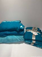 Four blue throws and a velvet reversible comforter neatly folded and tied with a silver ribbon.