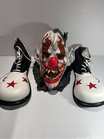 Full view of clown mask flanked by star print high-top boots.
