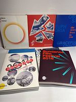 Photo showing six Sundance Film Festival guides arranged in two rows, various cover designs including 2016 and older editions.