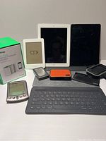 Front view image showing 2 tablets, Kindle, wireless blood pressure monitor box, Palm device, Tumi charger, and keyboard.