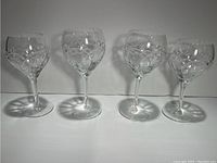 Four Waterford crystal wine glasses with intricate cut patterns, two taller red wine glasses and two shorter white wine glasses.