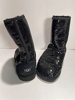 Front and back views of black sequin UGG boots showing the exterior sequin finish and plush lining inside