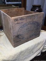 Photo showing the side of the wooden crate with finger joint corners and faded stamped Canadian Butter oval logo and text