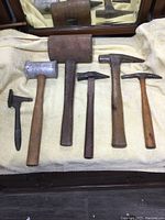 Photo showing full set of six antique hand tools including wood mallet, aluminum mallet, meat tenderizer, and four hammers with wooden handles.