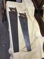 Both antique handsaws placed side by side showing length and shape differences