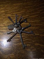 Several antique skeleton keys arranged on a wood surface on a key ring, showing a variety of designs and signs of rust and age.