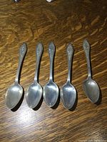 Top view of the set of five antique sterling silver spoons showing spoon bowls and handles.