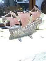 Front side view of the cast iron sailing ship showing three sails and detailed hull with aged patina and wear.