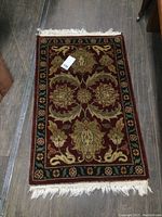 Full view of vintage wool rug 42x24 with floral pattern and visible fringe wear