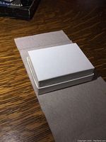 Closed white jewelry box on a wooden surface, showing packaging of the brooch.