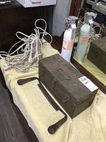 Metal toolbox, wooden handle draw blade, extension cords and fire extinguisher displayed on towel