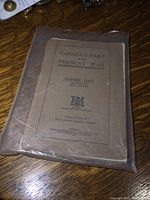 Photo of the front cover of the booklet 'Canada's Part in the Present War' published for Empire Day May 23, 1918, showing paper wear and edge creases.