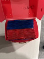 Top down image of a red open box filled with Yu-Gi-Oh! trading cards organized in two piles in red and blue sleeves.