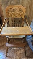 Front view of antique Dutch hand carved high chair showing detailed carved backrest, attached tray, armrests, spindled legs, and footrest.