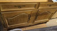 Close-up view of the lower section showing wood finish, curved panel doors, drawers, and brass handles.