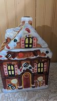 Front view of the ceramic gingerbread house cookie jar showing colorful detailing and window designs.