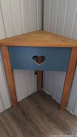 Corner pine table with blue front panel and heart cut-out photographed in corner space.