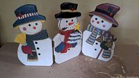 Trio of hinged wooden snowmen standing side by side showing overall condition and size.