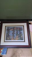 Framed and matted print titled Montreal River by Lawren Harris showing stylized landscape of trees, river, and hills.