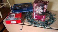 Boxes and various Christmas lights and decorations on a floor and table.
